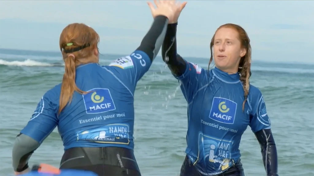 Deux participantes en combinaison MACIF se congratulent en sortie de mer, extrait de vidéo corporate Scriptonic sur l’inclusion par le sport